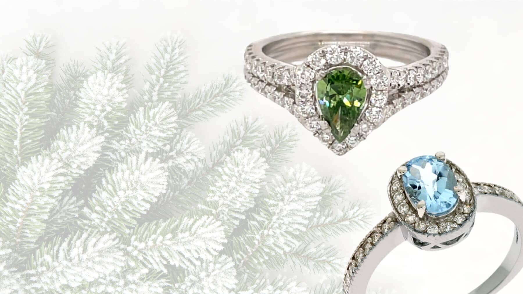 Two diamond fashion rings with green and blue gemstones, set against a frosted pine tree background for holiday elegance. Perfect for finding your festive statement piece.
