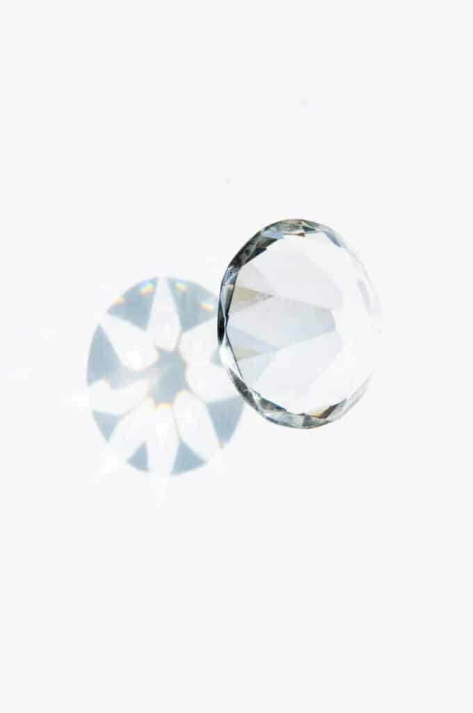 Top-down view of a loose diamond showing clear light refraction and a star-shaped shadow on a white background.