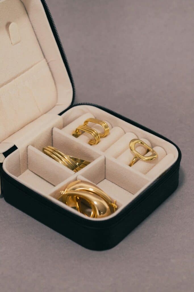 Gold rings and earrings safely stored in separate compartments inside a soft velvet travel jewelry organizer
